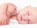 Ein friedlich schlafendes Baby, etwa 4 Monate alt, mit geschlossenen Augen und leicht geöffneten Lippen. Die zarte Haut und die kleinen Händchen sind gut zu erkennen.