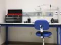 Warsztat z niebieskim stołem, na którym stoi skrzynka z narzędziami, telefon i lampa. Jaka wysokość stołu warsztatowego jest idealna do pracy?