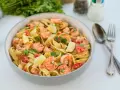 Pyszne tagliatelle z krewetkami, pomidorami i limonką, posypane świeżą natką pietruszki. Idealne danie na szybki obiad.