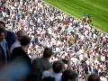 Foule nombreuse sur un hippodrome en France, spectateurs massés pour une course de chevaux.
