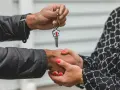 Une main tend une clé avec un porte-clés en forme de maison. Les deux mains se serrent, symbolisant la fin d'une obligation de relogement par la mairie.