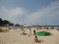 Słoneczna plaża w Darłowie tętni życiem. Ludzie opalają się, bawią z dziećmi i odpoczywają pod kolorowymi parawanami.