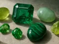 A collection of green gemstones, including a large emerald, showcasing the emerald meaning spiritual connection and growth.