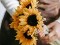 Manos sostienen un ramo de girasoles, flores que simbolizan la felicidad y la vitalidad.