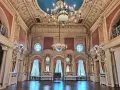 Wnętrze pałacu w Poznaniu, idealne do zwiedzania. Bogato zdobiony sufit, kryształowe żyrandole i eleganckie zasłony tworzą atmosferę dawnej świetności.