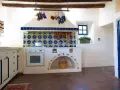 Cocina rústica con azulejos coloridos y detalles DIY, ideal para decorar casa de campo con poco dinero. Cestas y ollas cuelgan, creando un ambiente acogedor.