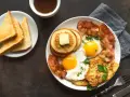 Esempio di colazione proteica per dimagrire: uova, bacon, pancake, toast e succo d'arancia.