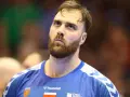 Andreas Wolf, zamyślony zawodnik w niebieskiej koszulce z herbem Kielc, patrzy w górę.
