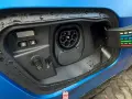 Gniazdo ładowania w niebieskim samochodzie. To pokazuje, co to jest plug-in hybrid – samochód, który można ładować z sieci.