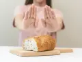 Osoba odrzuca chleb, sygnalizując uczulenie na gluten i laktozę objawy.