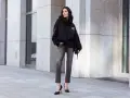 Kobieta w czarnej bluzie z kapturem i szarych jeansach. Luźny krój (loose fit) bluzy podkreśla swobodny styl.