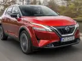 Czerwony Nissan Qashqai 2023 z napędem e-POWER jedzie po drodze, za kierownicą siedzi kierowca.