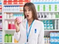Zaskoczona farmaceutka trzyma skarbonkę, zastanawiając się, ile zarabia technik farmacji.