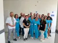 Grupa lekarzy i pielęgniarek w uniformach medycznych stoi w korytarzu szpitalnym.