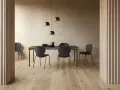 Jadalnia w stylu soft minimalism: czarne krzesła i stół na tle beżowej ściany, oświetlone lampami.