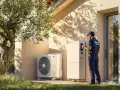 Técnico revisa sistema de aerotermia R290 junto a una casa moderna.