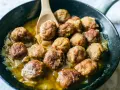Polpette in bianco dorate e succulente, cotte in padella con cipolle dolci e un sughetto invitante.