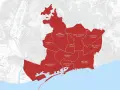 Mapa ukazuje podział Barcelony na dzielnice, zaznaczone na czerwono. Widać nazwy i liczbę mniejszych jednostek w każdej z nich, np. Horta-Guinardó (11 barrios).