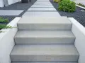Nowe schody do ogrodu zrób sam. Nowoczesne, betonowe stopnie prowadzą przez kamienny żwirek do zieleni.