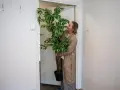 Mujer con planta en maceta en el rellano del piso, lista para entrar.