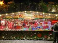 A vibrant Dresden Christmas market stall overflowing with gingerbread hearts, candied nuts, and colorful sweets. Festive lights twinkle above the tempting displays.