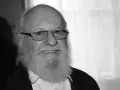 Uśmiechnięty Aleksander Skowroński z siwą brodą i okularami.