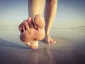Paluch biegacza pokryty piaskiem, stopy na mokrym piasku przy plaży.
