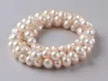 Collana di perle d'acqua dolce, simbolo di purezza e saggezza. Le perle sono disposte in un cerchio su sfondo grigio.