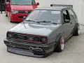Szary, zmodyfikowany Volkswagen Golf GTI z szerokimi błotnikami i spojlerem.