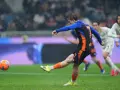 Piłkarz w niebiesko-czarnej koszulce z numerem 7 strzela gola w deszczu podczas meczu Inter Mediolan – AS Roma.