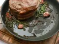 Rouelle de porc au barbecue, rôtie dans une poêle avec de l'ail et des herbes aromatiques, prête à être dégustée.