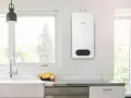 Scaldabagno a gas Bosch bianco, con pannello di controllo digitale, montato a parete in una cucina moderna.
