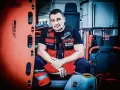 Ratownik medyczny w kamizelce z napisem "Paramedic" i "Ratownik Medyczny" siedzi w karetce obok noszy.