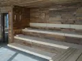 Drewniana sauna w domu z wielopoziomowymi ławami i kamienną podłogą. Idealne miejsce na relaks.
