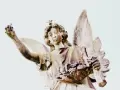 Kamienna figura anioła z gwiazdą na głowie, trzymająca w dłoniach kwiaty i gałązkę. Symbolika 2244 znaczenie.