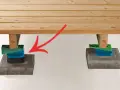 Stöd för att bygga trall: trästolpar vilar på justerbara klossar ovanpå stenplattor.