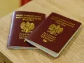 Dwa polskie paszporty leżące na drewnianym blacie.
