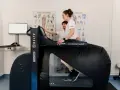 Donna in gravidanza usa un tapis roulant anti-gravità con un fisioterapista.
