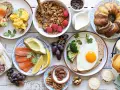 Leckeres Fingerfood für den Osterbrunch: Rührei, Lachs, Avocado, Kuchen, Muffins und Nüsse.
