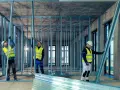 Budowlańcy montują konstrukcję ścian z profili UA. Praca na budowie postępuje.