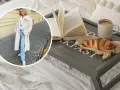 Kobieta w płaszczu z owczej wełny, symbolizującym quiet luxury, cieszy się śniadaniem w łóżku: książka, croissant i kawa.