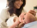 Lächelnde Mutter hält ihr Baby, das gerade einen Wachstumsschub durchmacht.