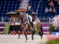 Une cavalière en tenue d'apparat, Sandro Hit, exécute une figure de dressage devant un public.