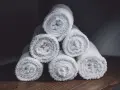 Toallas blancas enrolladas, listas para lavar en la lavadora y quedar esponjosas.