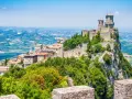 Trzy wieże obronne górują nad malowniczym krajobrazem San Marino, otoczone zielenią i historyczną zabudową.