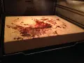 Ein schmutziger pizzastein mit braunen Flecken und Essensresten, der im Ofen liegt.