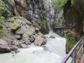 Aare Gorge, with its powerful river and dramatic cliffs, leads towards the Reichenbach Falls. A wooden walkway hugs the canyon wall.