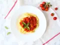 Penne z sosem pomidorowym i bazylią, obok świeże pomidorki koktajlowe.