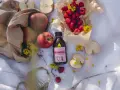 Naturalny ocet malinowo-jabłkowy, który może pomóc na zgagę. Wokół jabłka, maliny i żółte kwiaty.