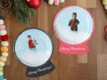 Dwie personalizowane kule śnieżne ze zdjęciami dzieci i płatkami śniegu.